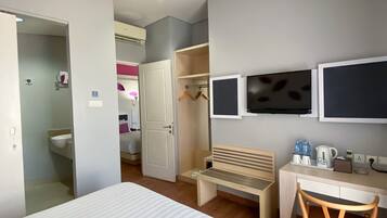 Una habitación de hotel con cama, escritorio, silla, armario y televisor.