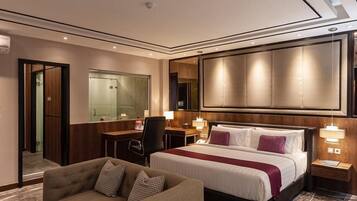 A modern hotel room with a large bed, a sofa, a desk, and a mirror.