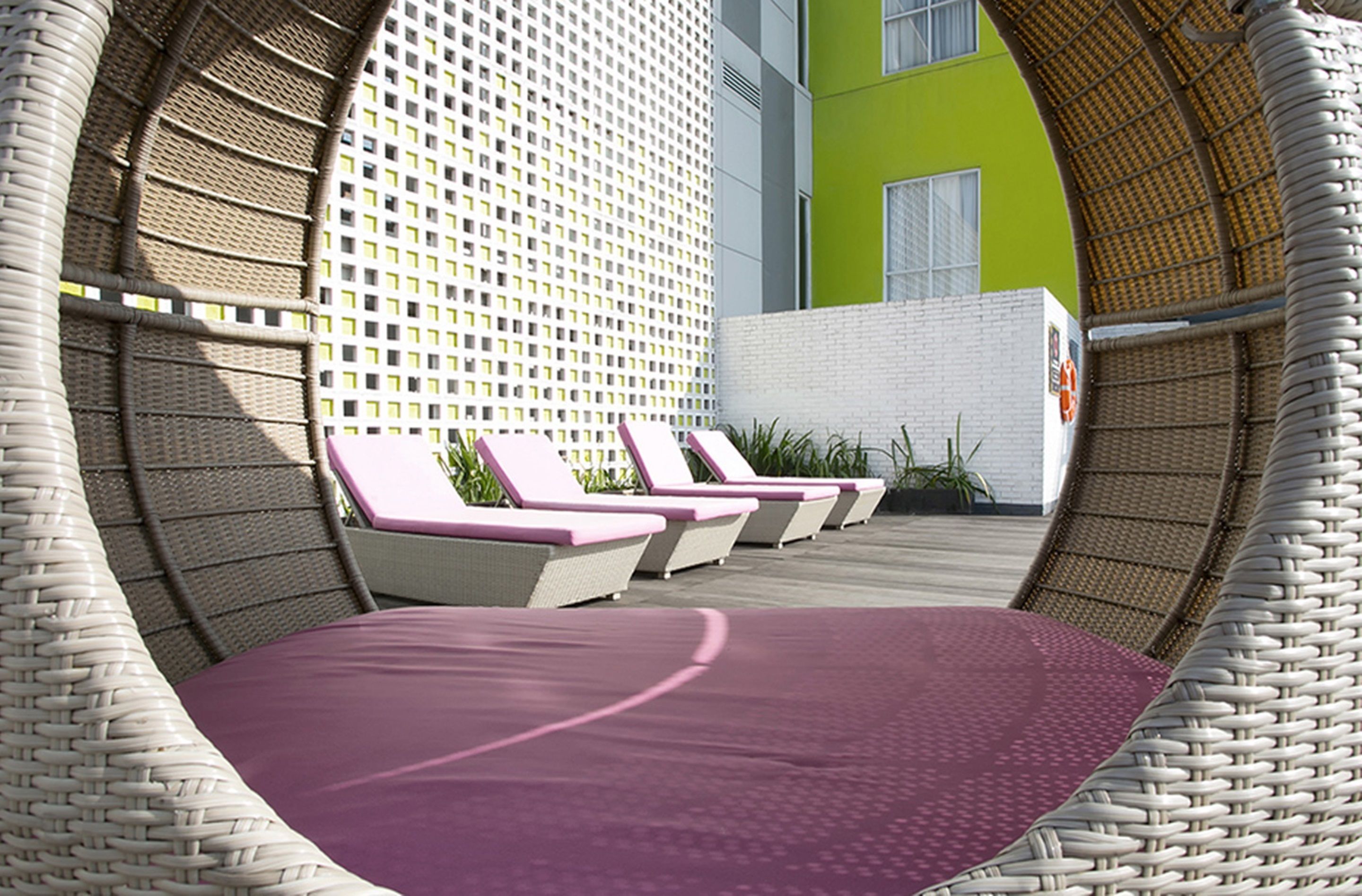 A circular outdoor seating area with wicker chairs and a purple cushioned bench.