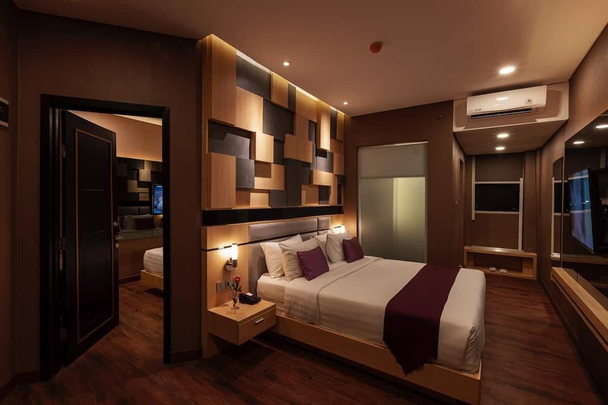 Ein modernes Hotelzimmer mit einem großen Bett, Nachttischen, einer Klimaanlage und Blick auf die Stadt.
