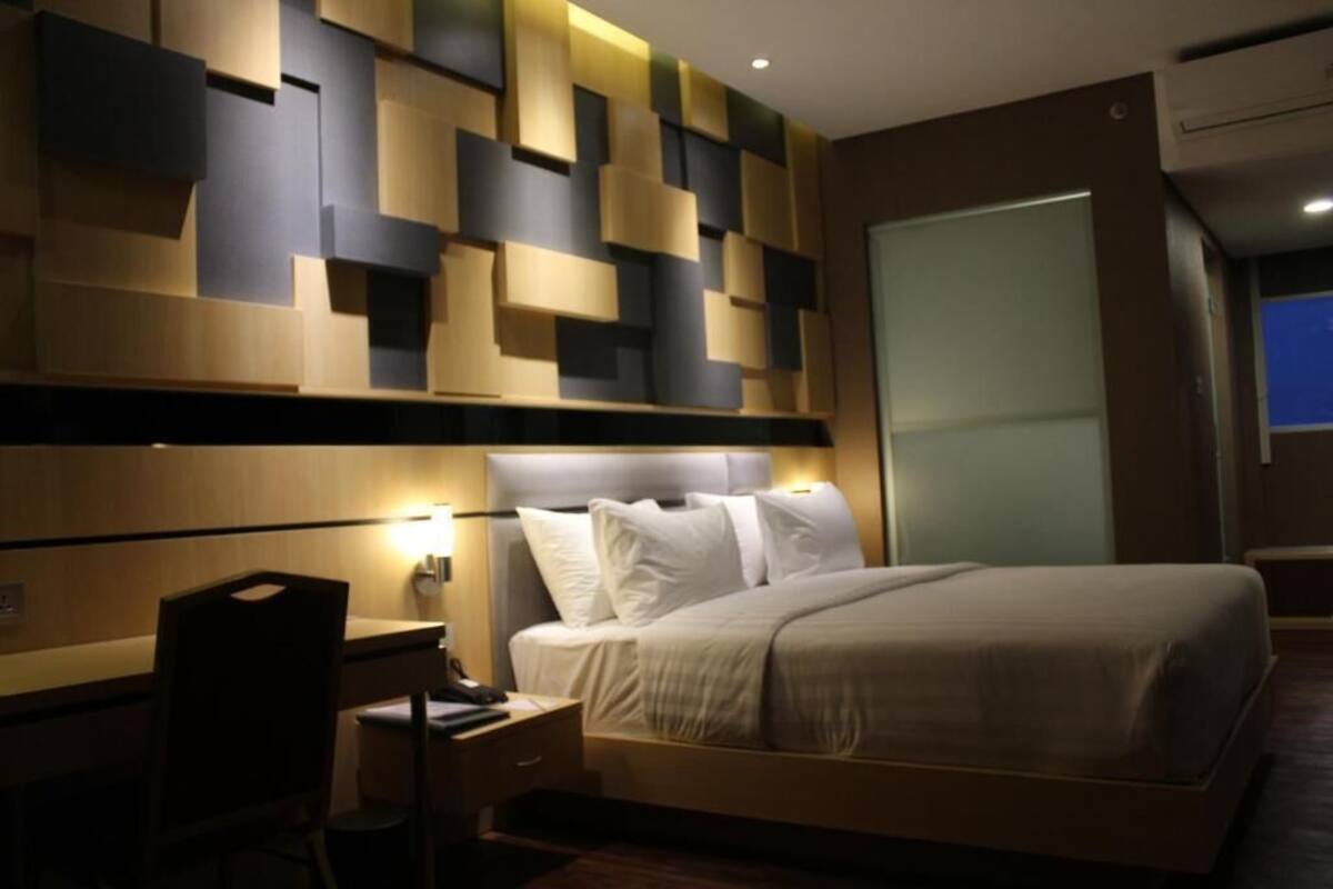 Ein modernes Hotelzimmer mit Bett, Nachttisch und Schreibtisch mit Stuhl.
