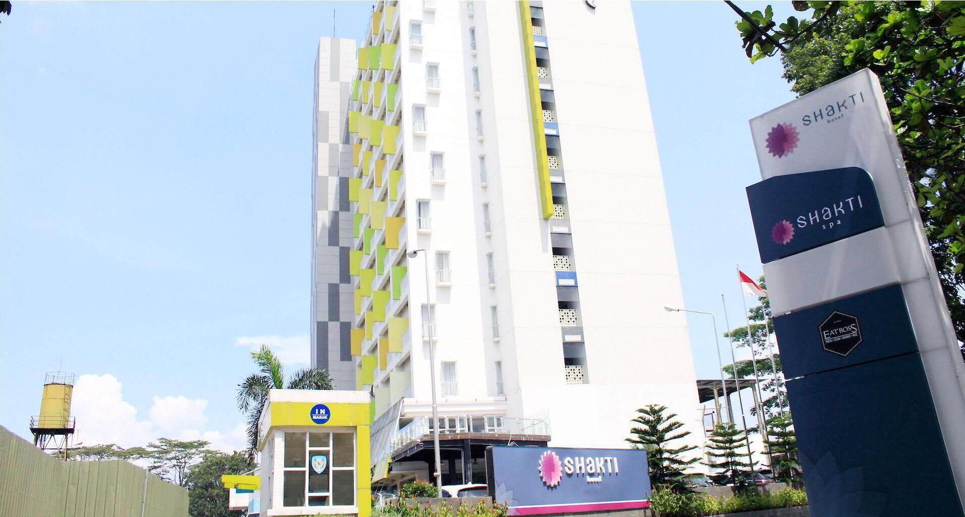 A modern building with a sign for Shakti hotel and spa, featuring balconies and a clear sky.