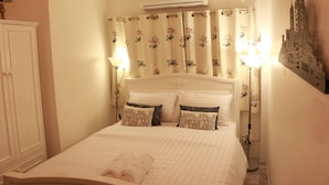 Une chambre à coucher avec un lit, des rideaux blancs, un climatiseur fixé au mur et deux lampes de chevet.