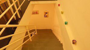 Un escalier avec des rampes blanches et des marches sombres, menant à un palier orné d’une inscription « LOVE » et d’un petit objet décoratif.