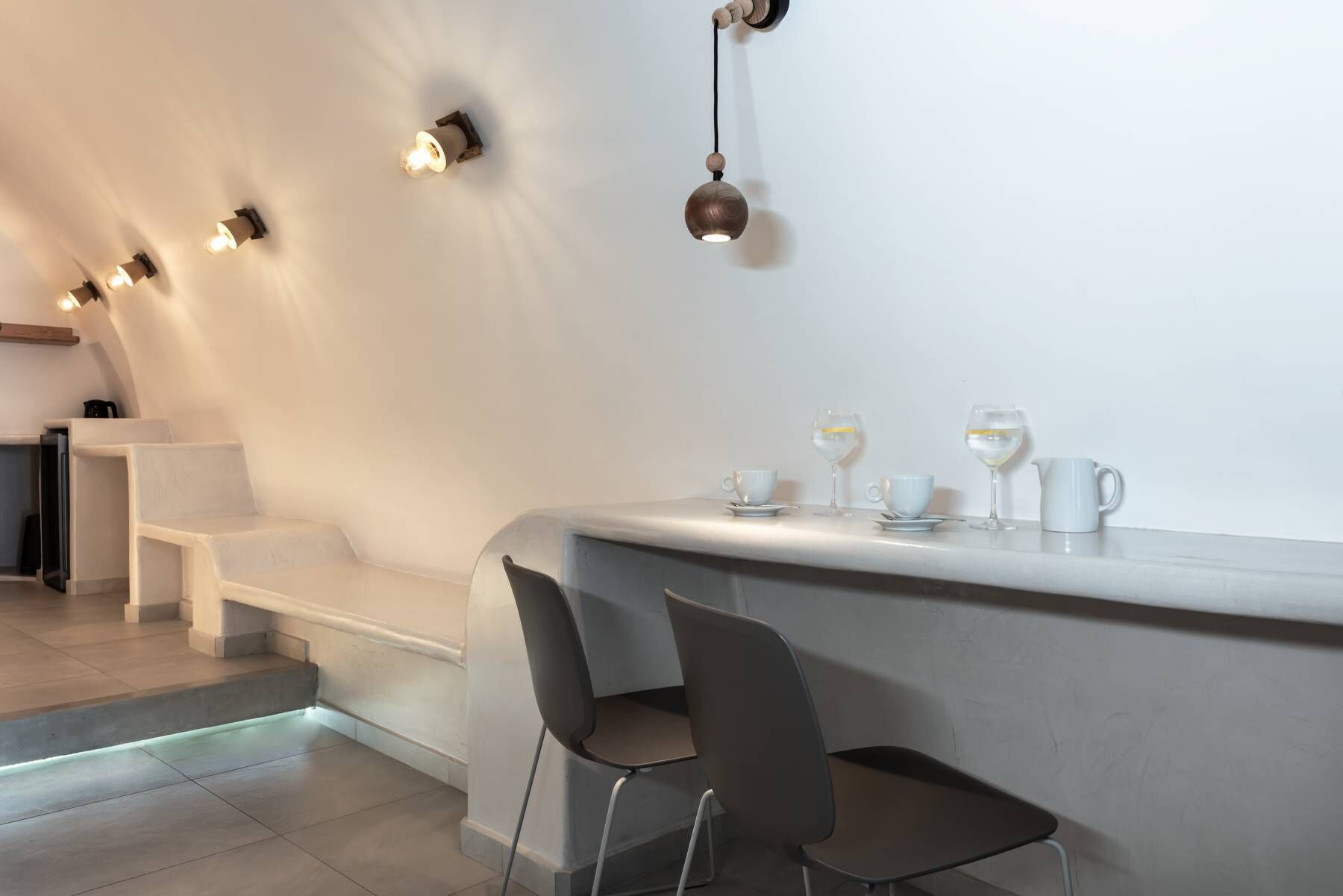 Eine moderne Bar mit einer gebogenen Theke, minimalistischen Stühlen und einer Sitzecke mit Stufen.