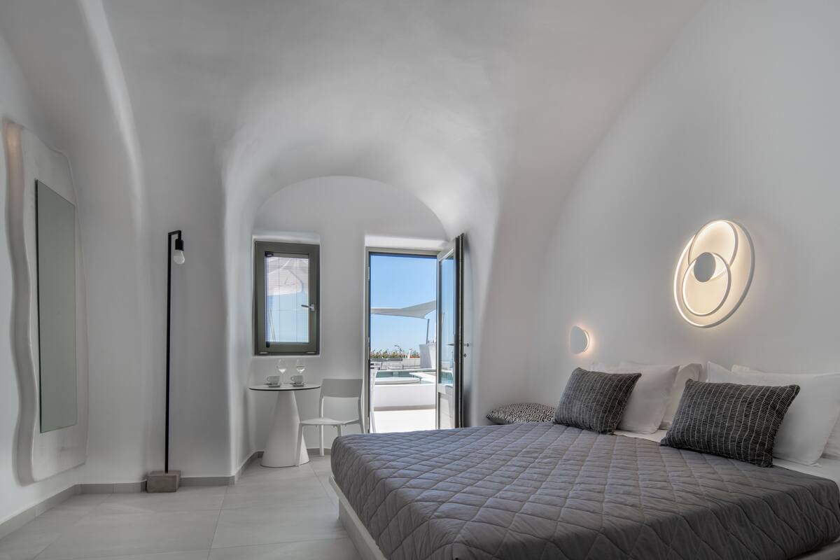 Ein modernes Schlafzimmer mit einem großen Bett, einem kleinen Schreibtisch und Blick ins Freie.