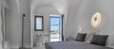 Een moderne slaapkamer met een groot bed, een klein bureau en uitzicht op de omgeving.