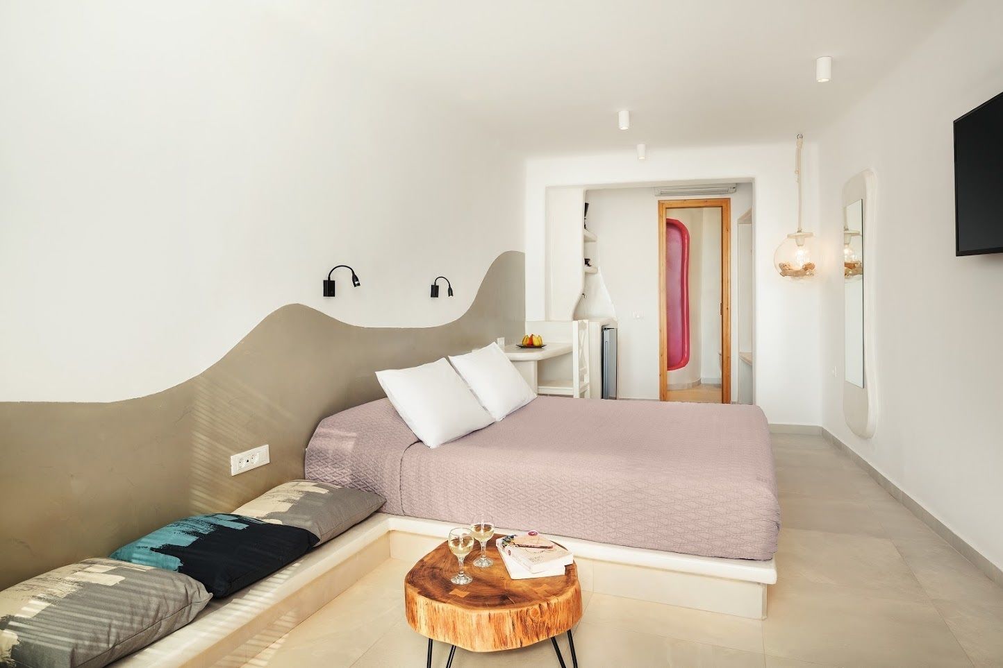 A modern bedroom with a bed, bedside table, and a small wooden stool.
