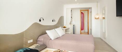 A modern bedroom with a bed, bedside table, and a small wooden stool.
