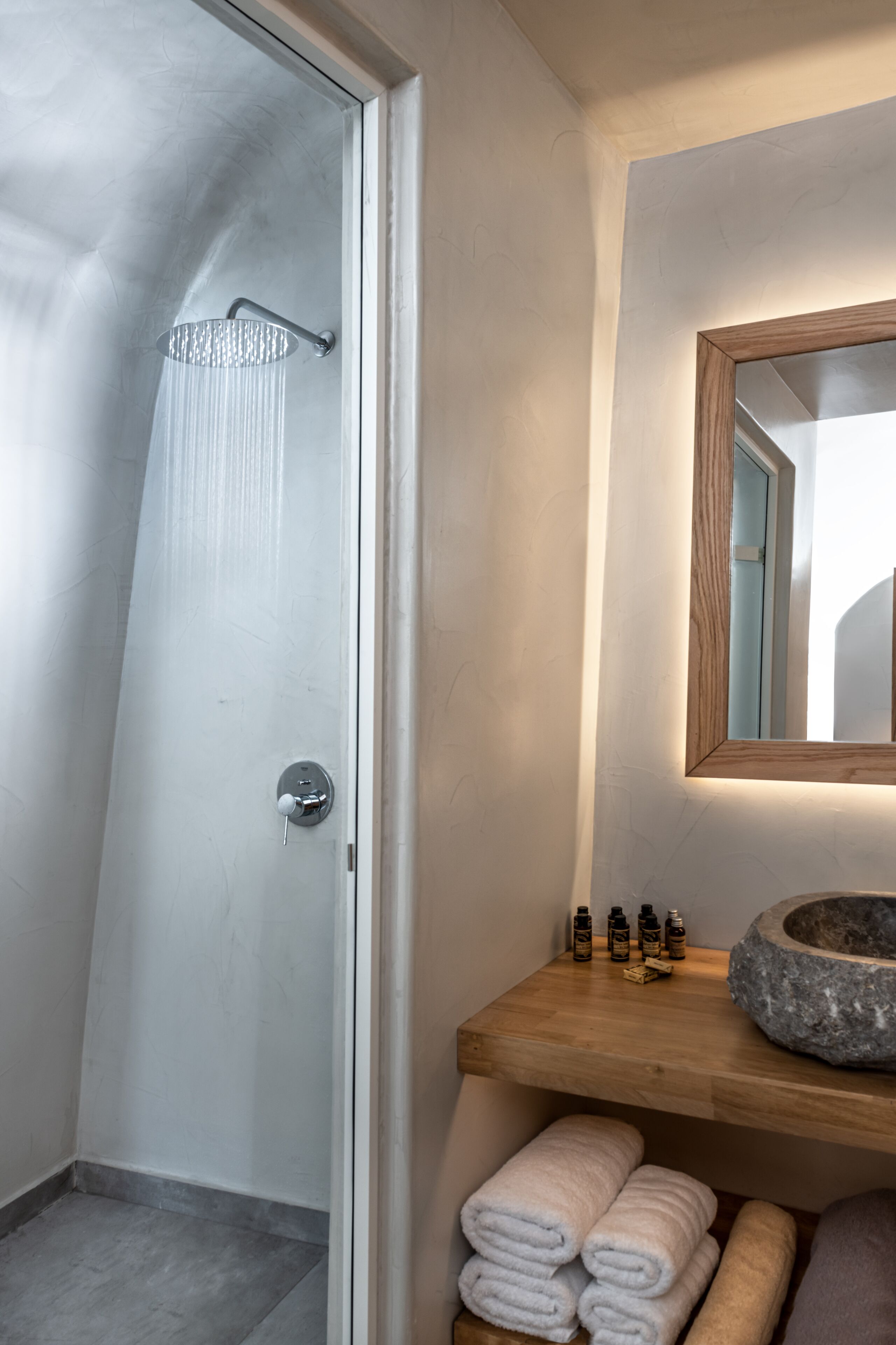 Un baño moderno con ducha, tocador de madera y un espejo.