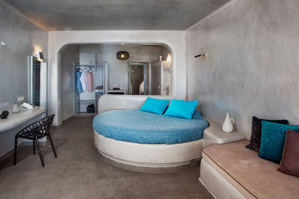 Ein kleines Schlafzimmer mit einem runden Bett, einem kleinen Schreibtisch und einer Sitzecke.