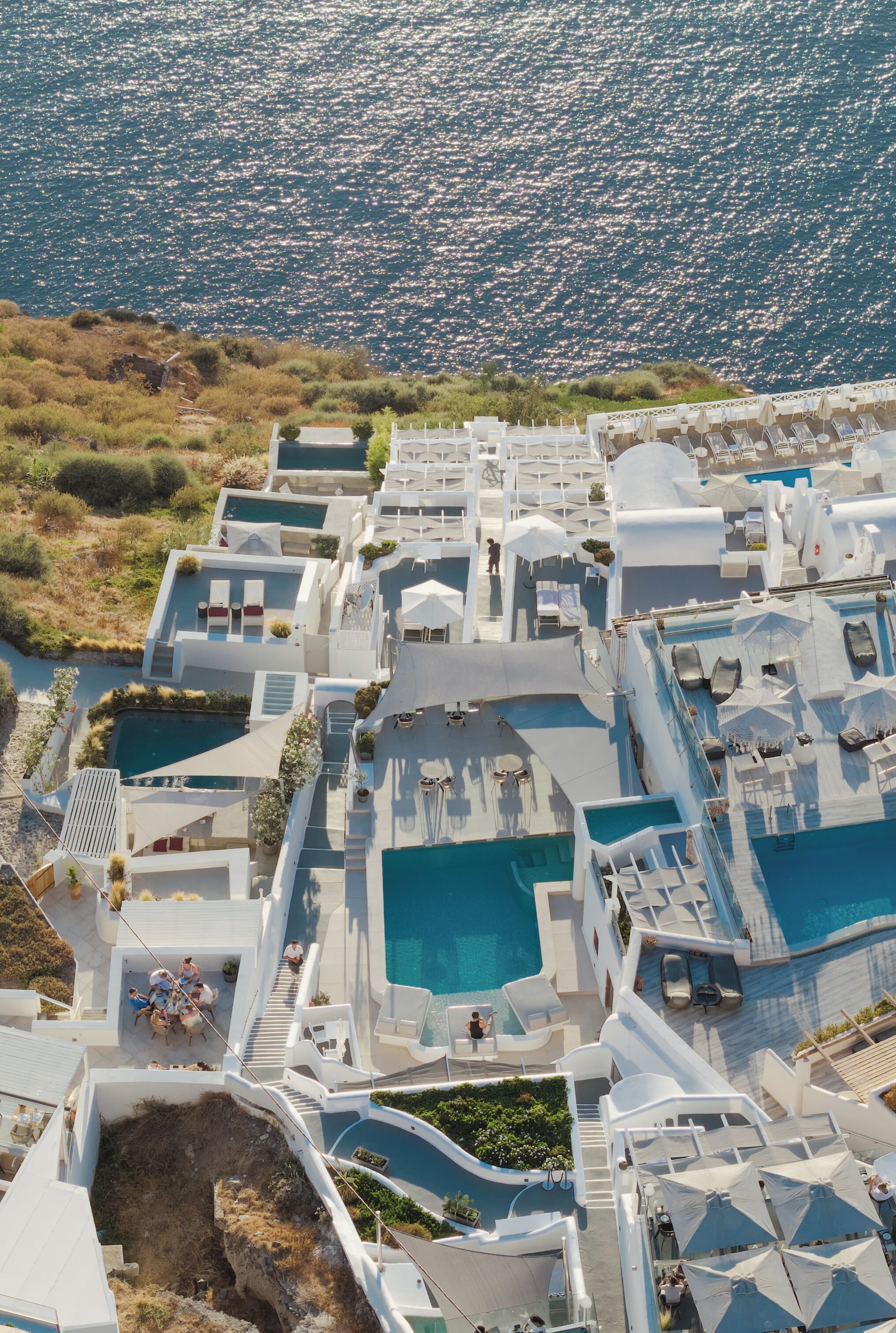 Vue aérienne d’un complexe hôtelier doté de plusieurs piscines, de chaises longues et offrant une vue dégagée sur la mer.