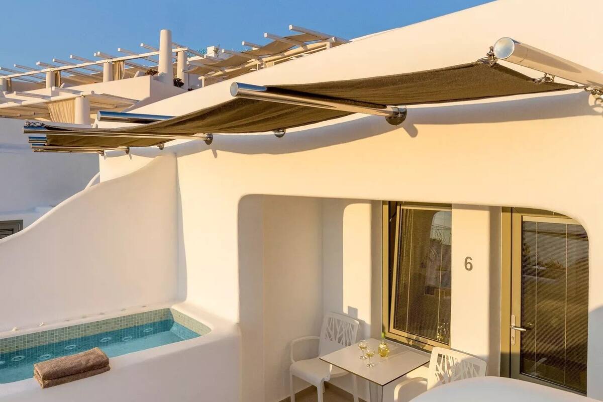 Ein moderner Balkon mit Pool, weißen Möbeln und einer Glastür.