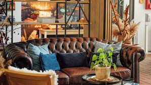A cozy living room with a leather sofa, wooden side tables, and a bookshelf filled with books and decorative items. - Aqua Hotel (Konstanz)