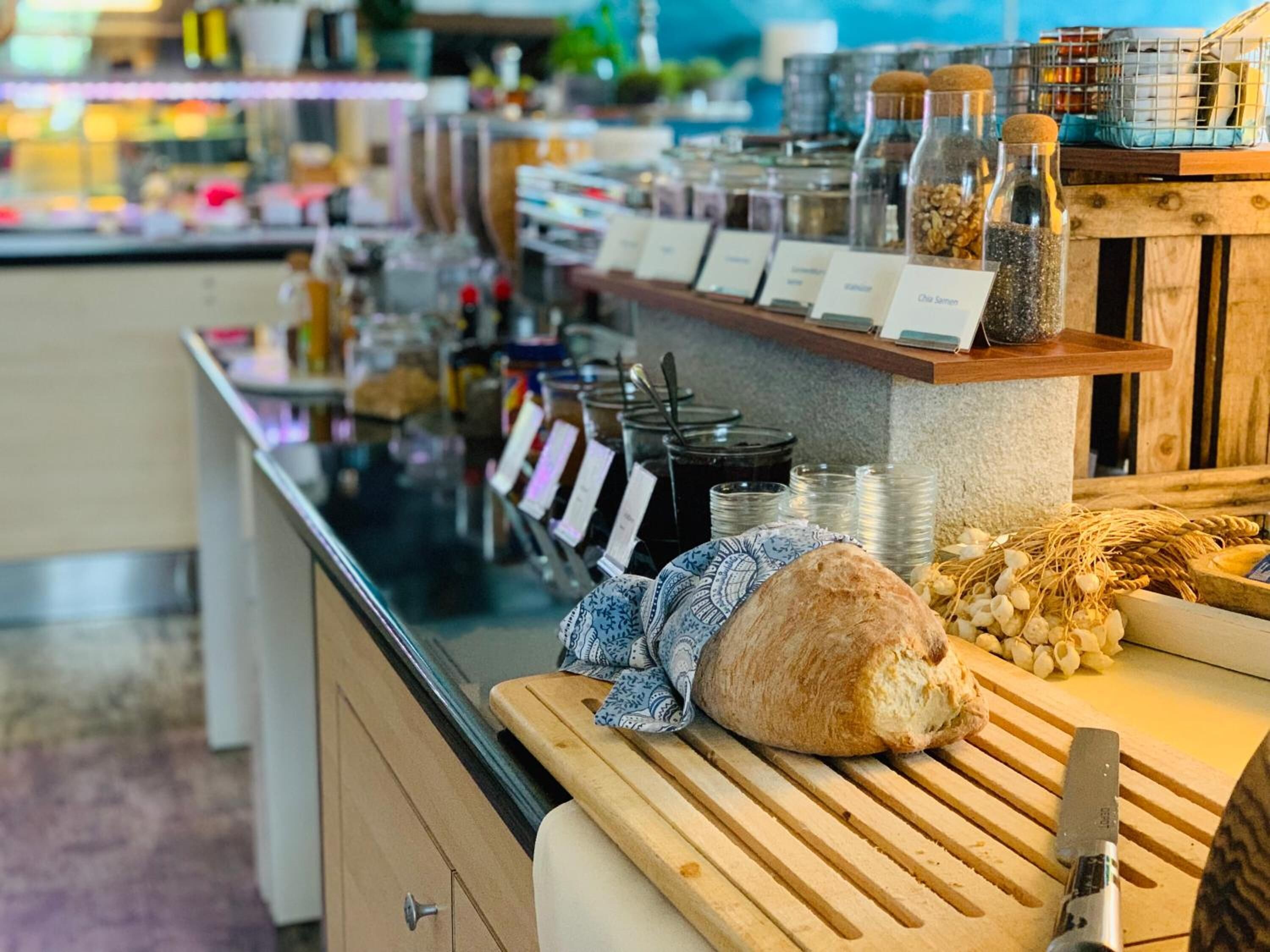 A bakery counter with a loaf of bread, jars of ingredients, and a knife.