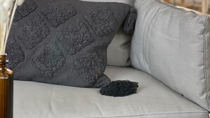 A grey sofa with a textured grey pillow and a plain grey pillow. - Aqua Hotel (Konstanz)