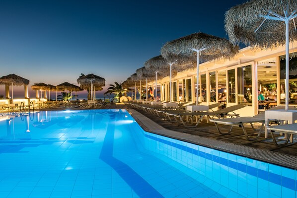 Alberca al aire libre, sombrillas en la alberca y camastros