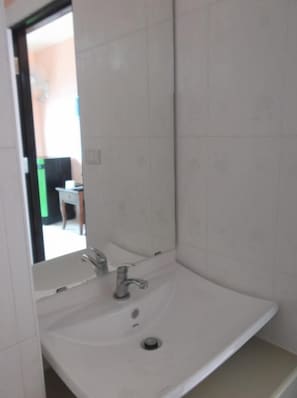 A bathroom with a white sink, a mirror, and a door leading to another room. - Moon Travel Guesthouse (Ko Pha-ngan)