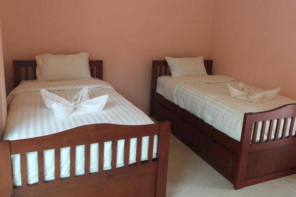 Une chambre avec deux lits simples, chacun doté d’une tête de lit en bois et de linge de lit blanc.