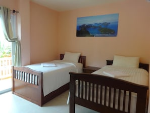 Een hotelkamer met twee bedden, een schilderij aan de muur en een raam met gordijnen.