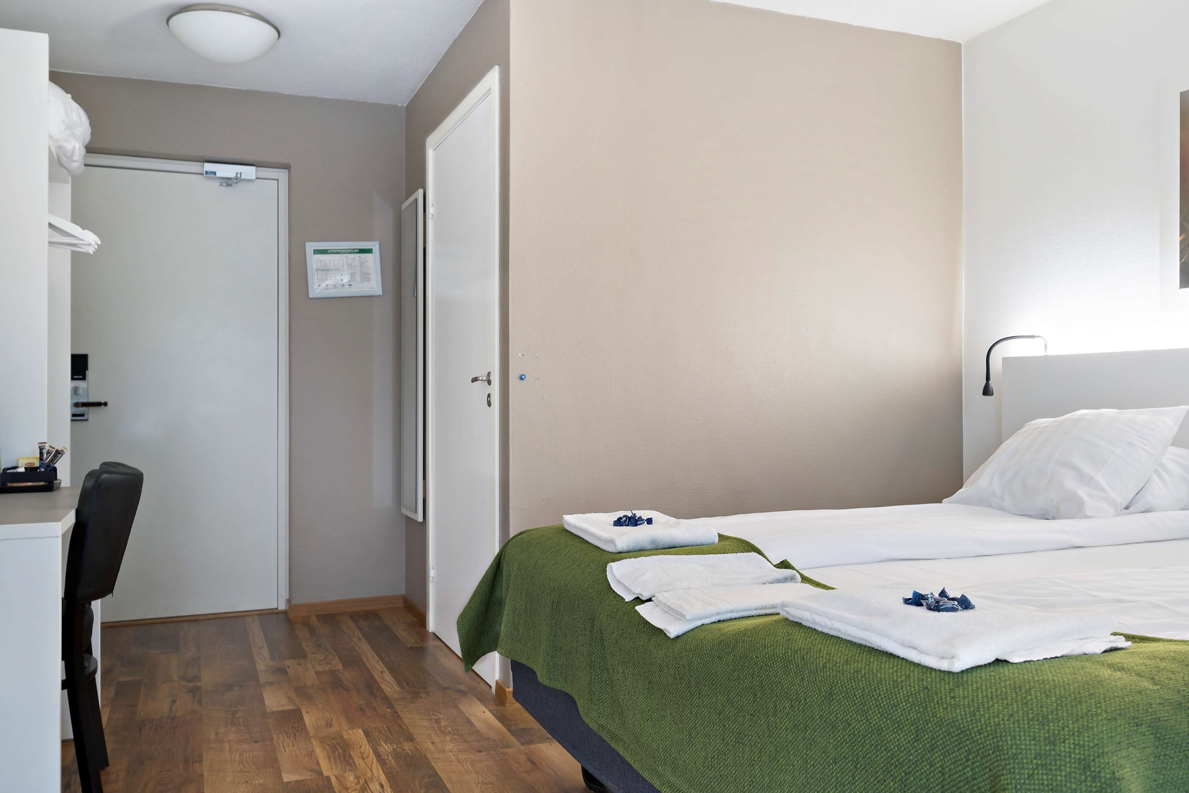 A hotel room with a bed, a desk, and a chair.