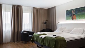 Ein Hotelzimmer mit einem Bett, einem Sessel und einem Bild eines Rehs an der Wand.
