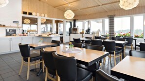 Ein modernes Restaurant mit Holzeinrichtung, schwarzen Stühlen und großen Fenstern mit Blick.