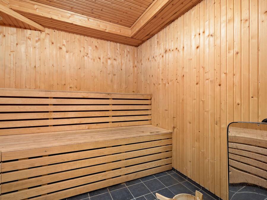 Uma sauna de madeira com bancos e piso revestido de azulejos.