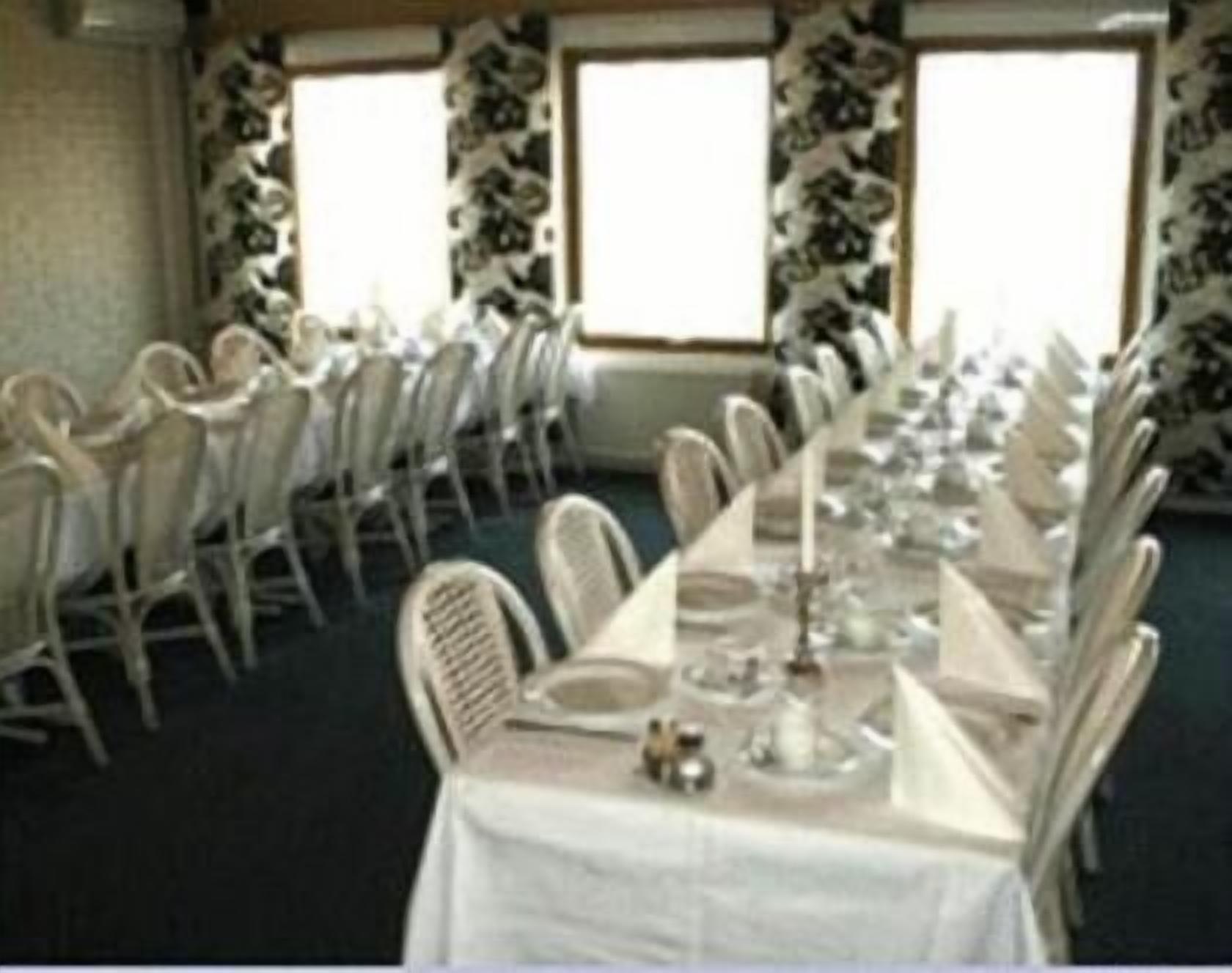 Une salle de banquet avec des rangées de chaises et de tables blanches, préparée pour un événement officiel.
