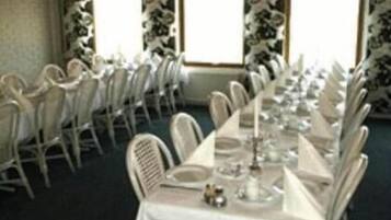 A banquet hall with rows of white chairs and tables set for a formal event.