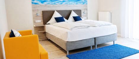 A modern bedroom with a bed, a nightstand, a chair, and a blue rug.