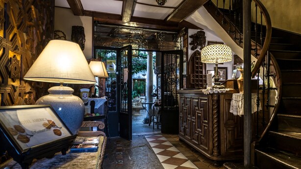 Un hall d’hôtel avec un sol à carreaux, un escalier et un coin bar agrémenté d’une lampe.