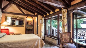 Une chambre avec un grand lit, une chaise, une table, un miroir et une vue sur l’extérieur.