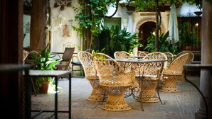 Une terrasse extérieure avec des meubles en osier et un sol carrelé.
