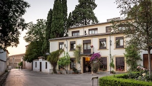 Un bâtiment à deux étages doté d’une cour intérieure, avec un chemin en pierre, des plantes en pot et une enseigne indiquant la présence d’un restaurant.