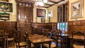 Une salle à manger traditionnelle, avec des meubles en bois, un lustre et des œuvres d’art encadrées accrochées aux murs.