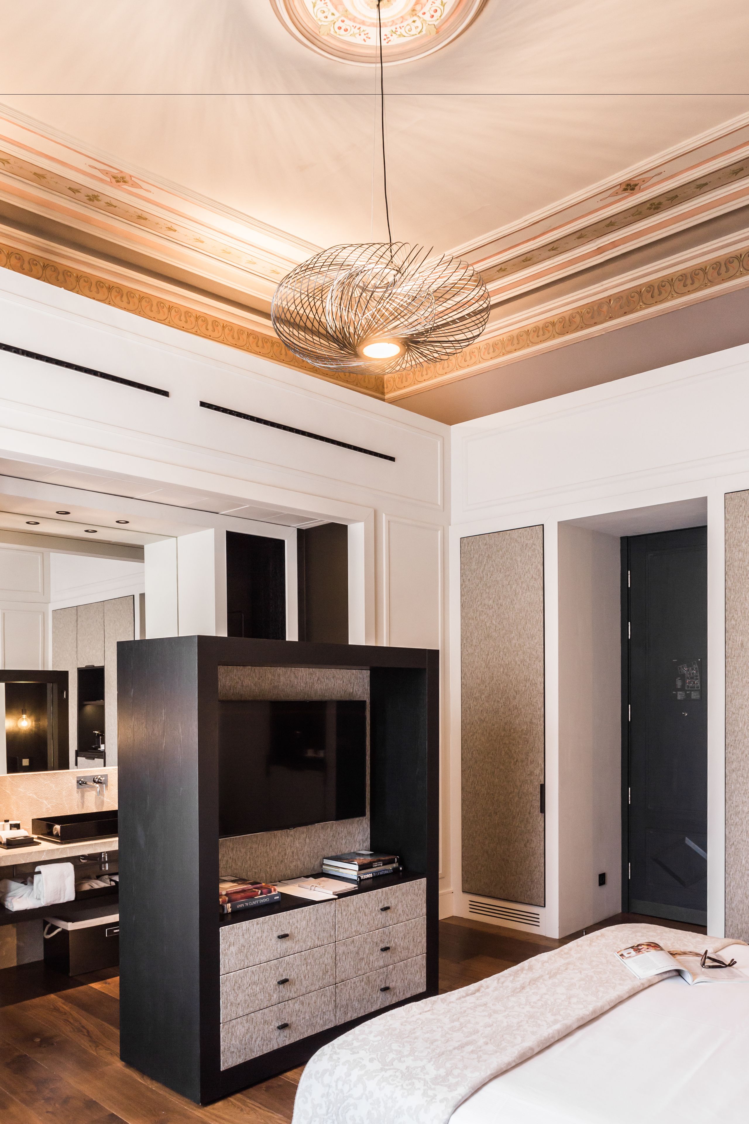 Une chambre moderne avec un grand lit, une armoire intégrée, une coiffeuse avec un miroir et un luminaire au plafond.