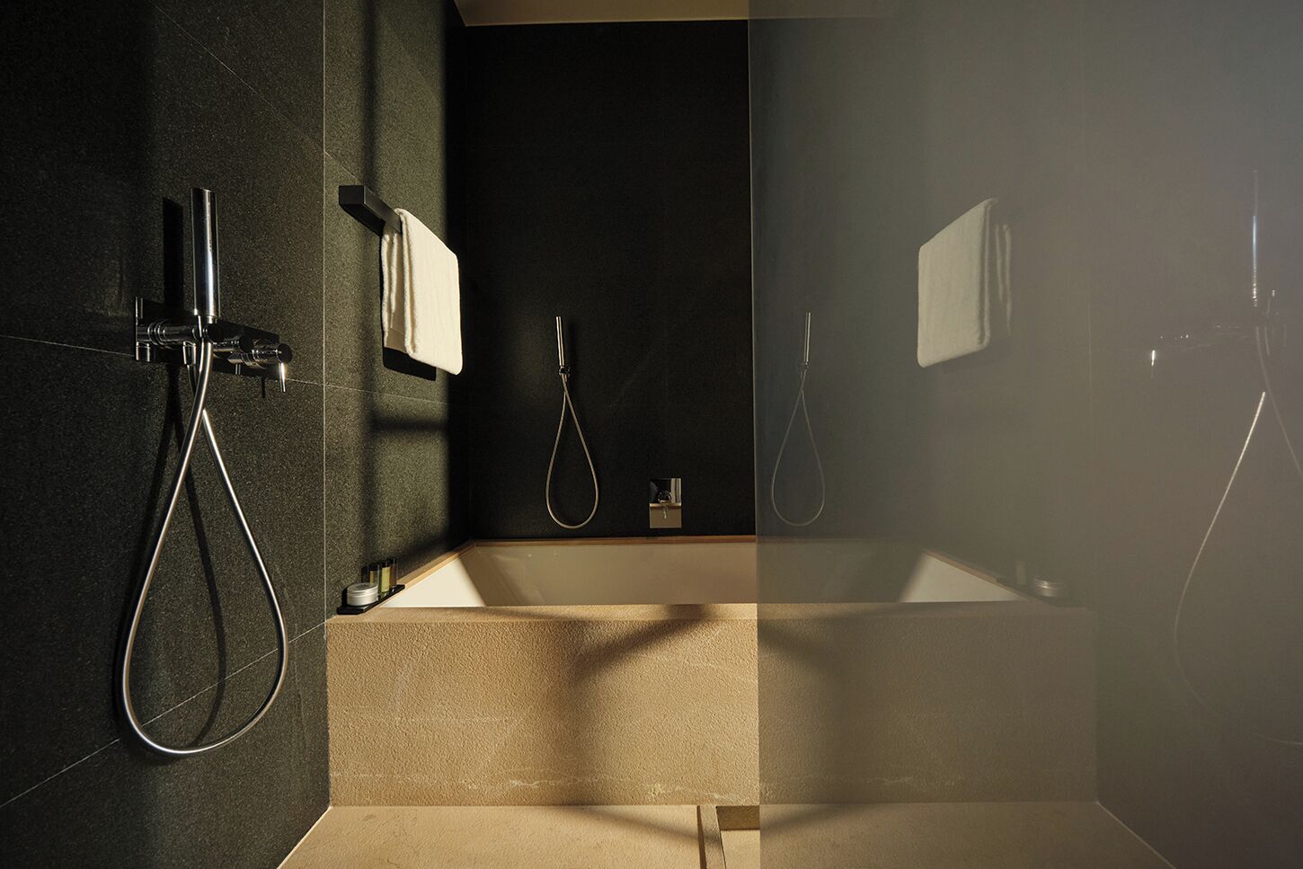 A modern bathroom with a bathtub, two showers, and a towel rack.