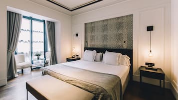Habitación de hotel con una cama grande, un banco, un escritorio, una silla y vistas al exterior.