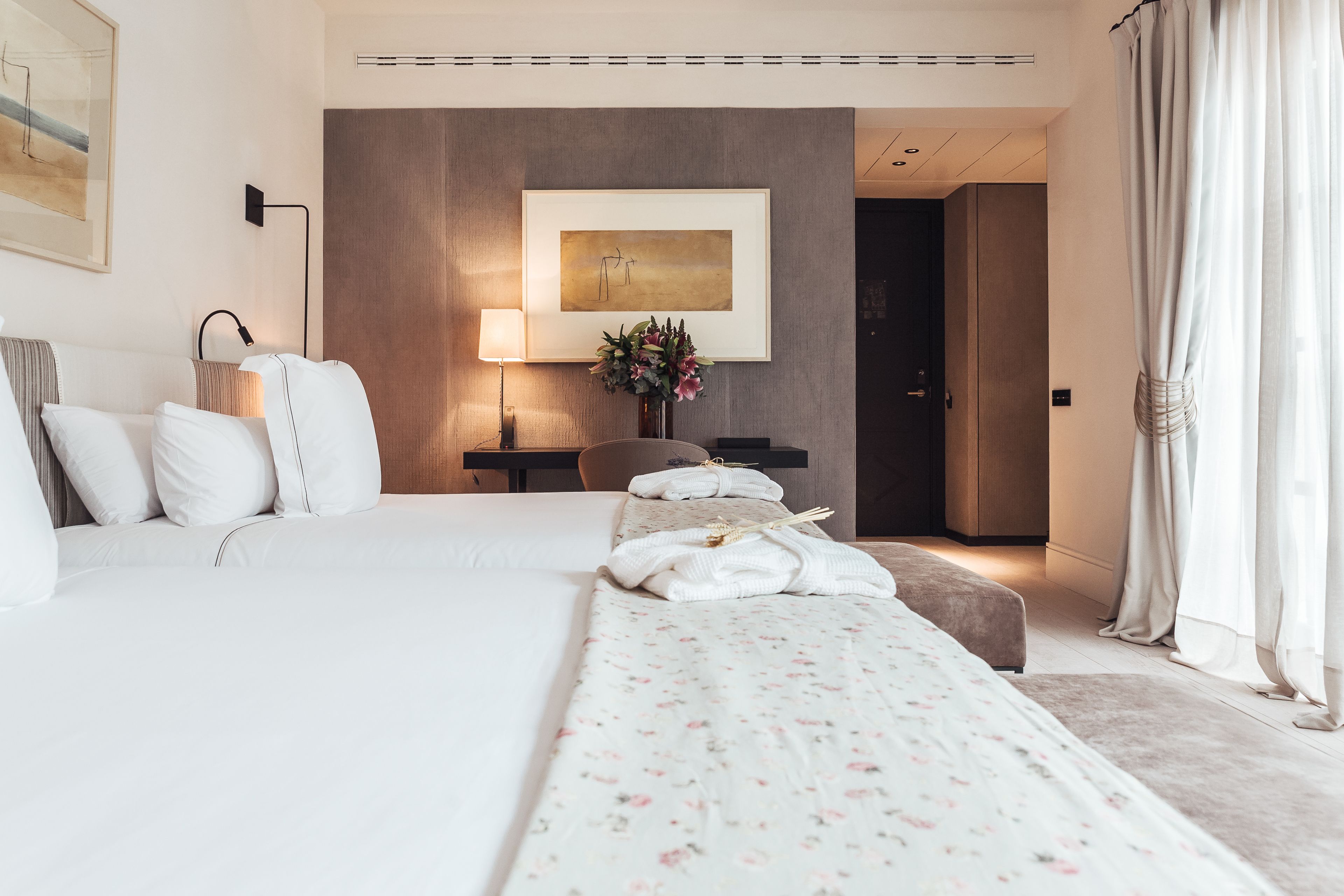 Een moderne hotelkamer met een groot bed, een bureau en een lijst met een kunstwerk aan de muur.