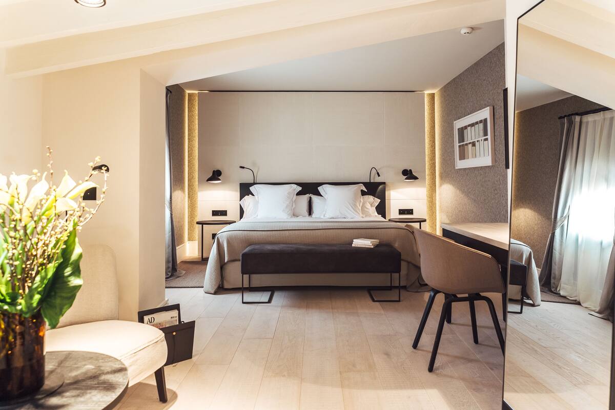 A modern hotel room with a large bed, bedside tables, a desk, and a chair.