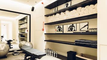 A gym with exercise equipment, towels, and shelves with framed pictures.