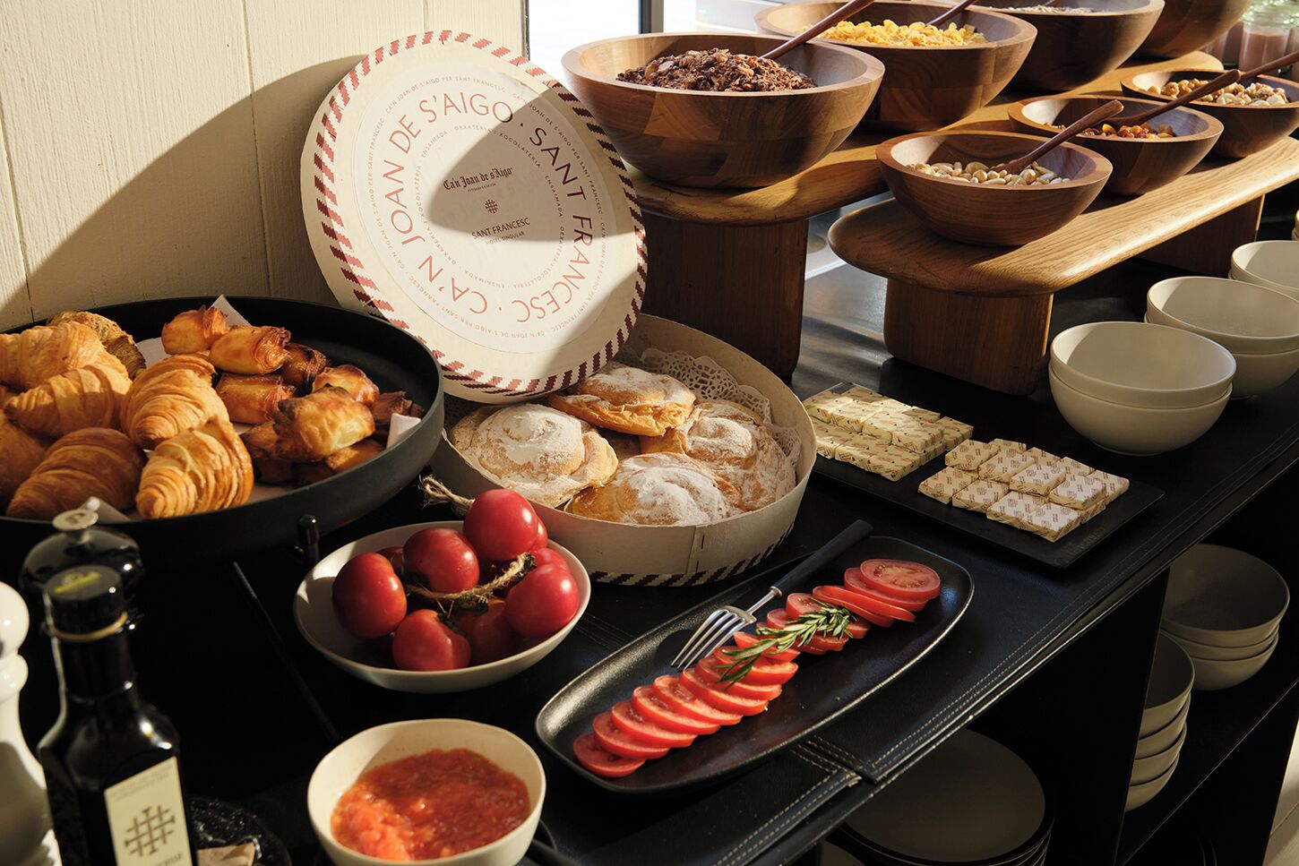 A buffet with various food items including croissants, bread, and tomatoes.
