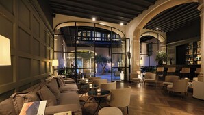 Amplia sala de estar con diseño moderno, que incluye un sofá grande, varias sillas y un bar con vistas a la terraza exterior.