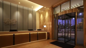 A modern reception area with a wooden reception desk, a glass door entrance, and a view of the outside. - Holiday Inn Express Haikou West Coast by IHG (Haikou)