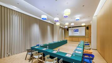 A conference room with a long table, chairs, and a projector screen.