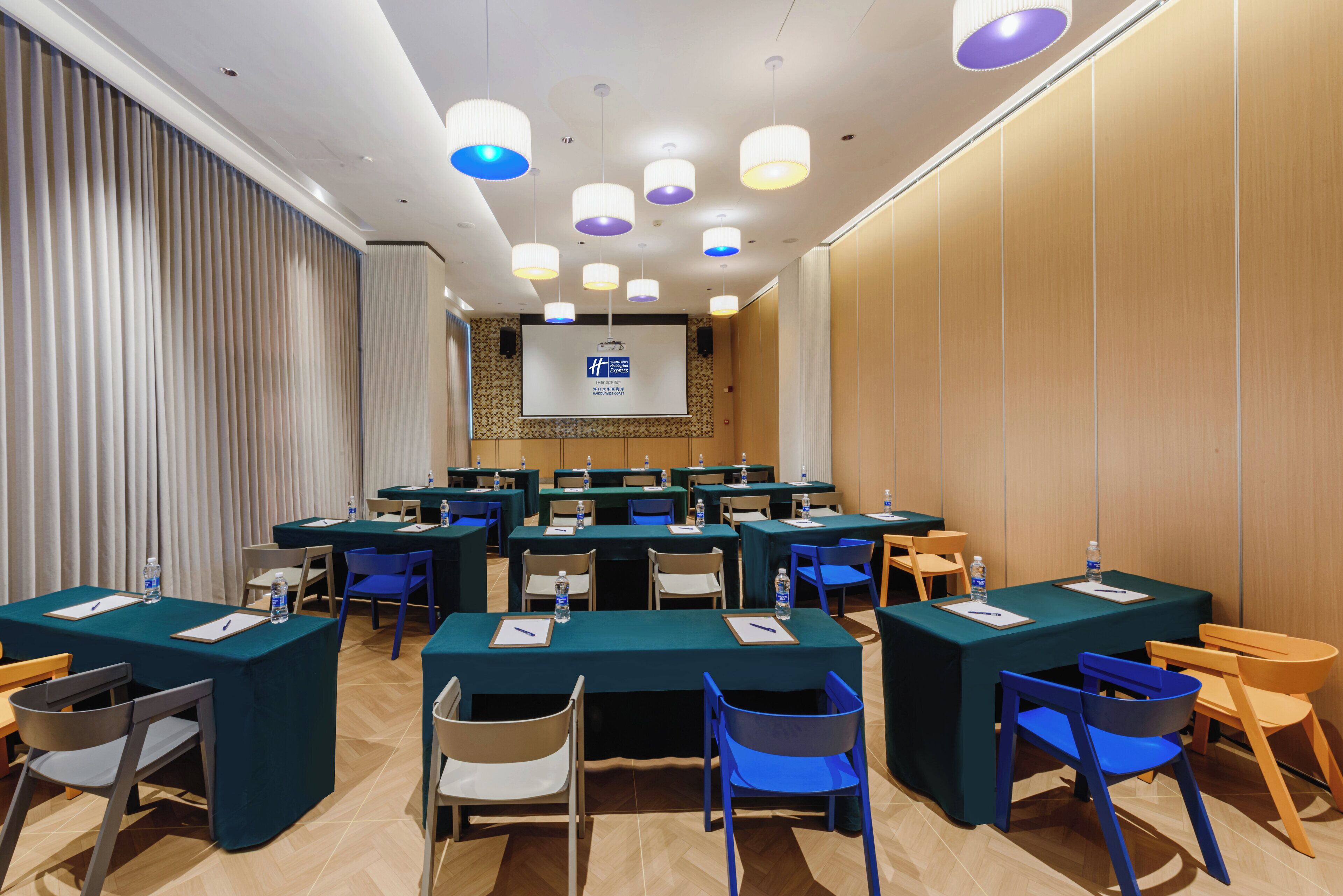 A conference room with multiple tables and chairs, equipped with water bottles and notepads.