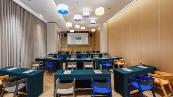 A conference room with multiple tables and chairs, equipped with water bottles and notepads.