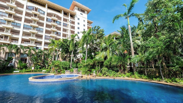 A hotel with a large swimming pool surrounded by lush greenery and palm trees. - Holiday Inn Express Haikou West Coast by IHG (Haikou)