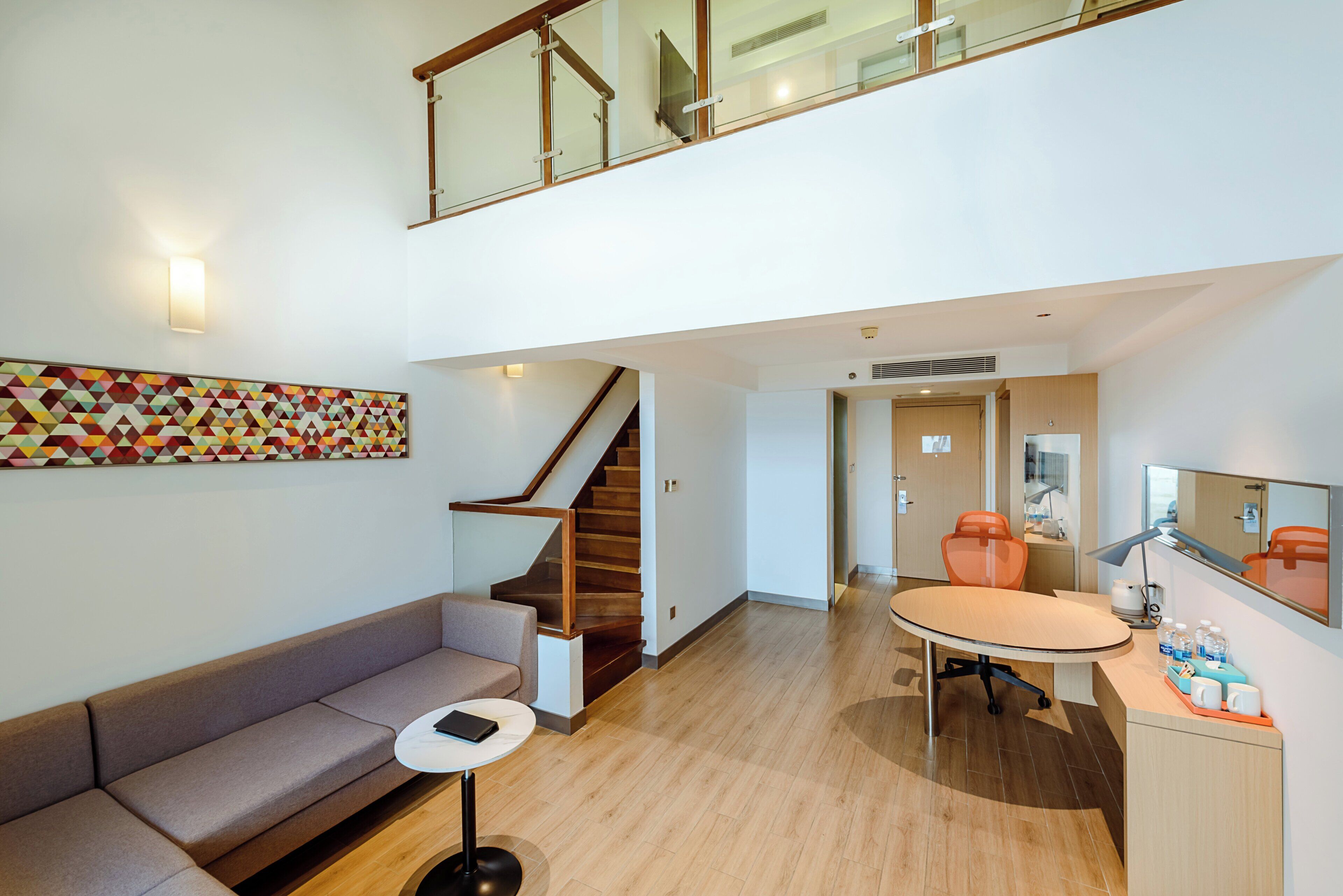Un interior moderno con una escalera, un sofá, una mesa de comedor y una zona de cocina.